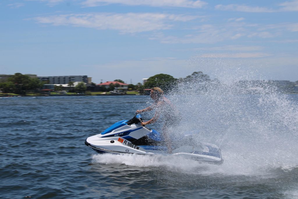 A Boy Riding A Jet Ski And Creating A Splash Of Water Behind Him.